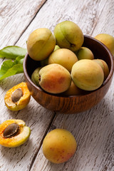 Naklejka na ściany i meble ripe organic apricots fruits in ash tree wooden bowl on a white wooden background