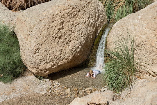 one person enjoying a natural massage under a small waterfall in the nahal david stream in israel surrounded by travertine boulders