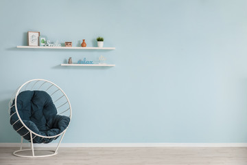 Stylish armchair near color wall in room