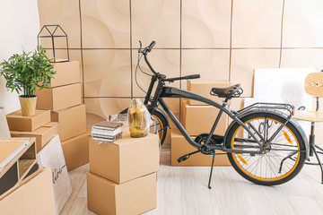 Cardboard boxes with belongings and bicycle in new flat on moving day