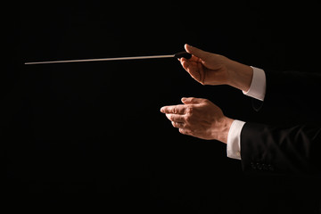 Hands of male conductor on dark background