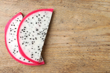 Slices of delicious dragon fruit (pitahaya) on wooden table, flat lay. Space for text