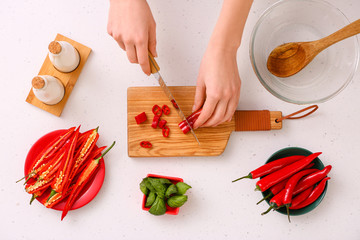 Woman cutting hot chili pepper, top view