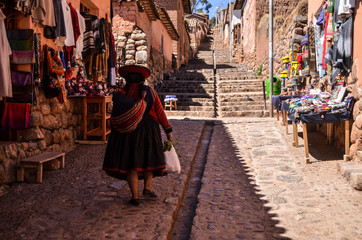 Woman in traditional Peruvian clothings walking in Chinchero, Peru.