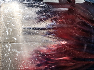 Auto glass in foam and water at a car wash as a backdrop.