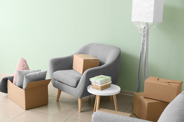Cardboard boxes with belongings and armchair in new flat on moving day