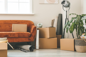Cardboard boxes with belongings and sofa in new flat on moving day