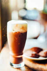 Iced cocoa drink  with whipped cream and Brownie cookies on wood table.