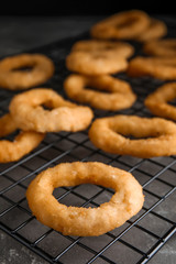 Cooling rack with fried onion rings on grey table