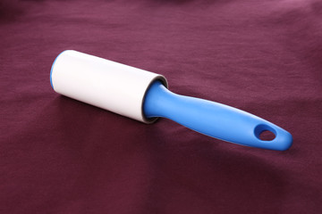 New lint roller with blue handle on red fabric