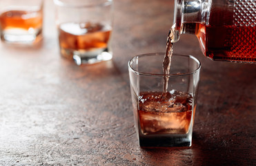 Pouring whiskey in glass with natural ice.