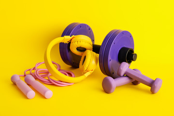 Fototapeta na wymiar Different sports equipment with headphones on color background