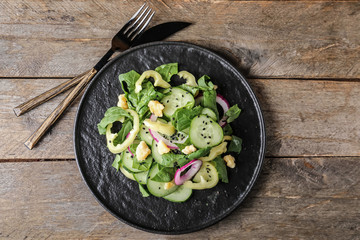 Plate with tasty cucumber salad on table