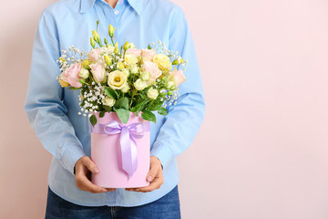 Woman with bouquet of beautiful flowers on light background