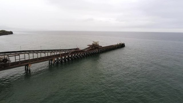 Aerial view Raynes jetty coastal quarry mining marine cargo landmark North Wales high push in orbit right