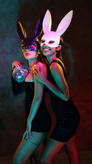 Portrait of two young flirting cute Asian women in black and white rabbit mask playfully posing for...