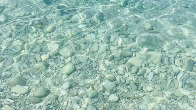 Transparent water of Ionian Sea Albania summer vacation. Ripples on water stones on the bottom