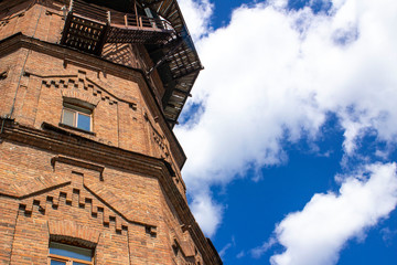 old water tower made of ancient bricks on a background of blue sky with clouds