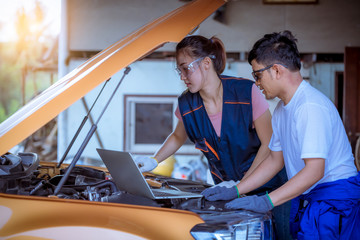 Man car technician mechanic under training woman mechanic to repairs and check car problem system check detail by laptop for maintenance and fixed in car garage.