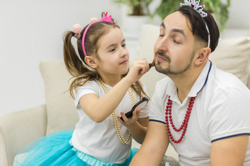 Cute little girl making makeup to her dad.