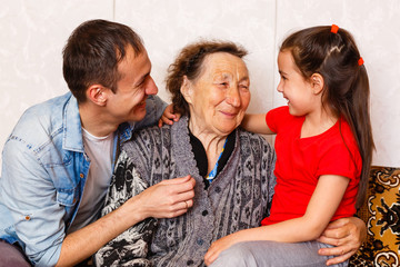 95-year-old woman and her great-granddaughter look at the camera. She is sitting on a chair in her living room.