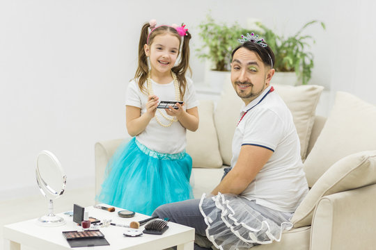 Cute little girl making makeup to her dad.