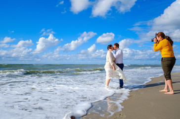 Photographer taking picture of kissing couple near sea