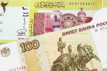 A macro image of a Russian one hundred ruble note paired up with a green two pound bank note from Sudan.  Shot close up in macro.