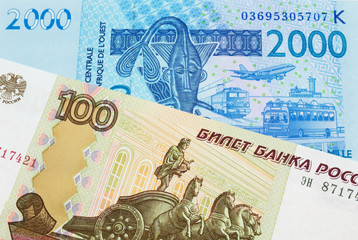 A macro image of a Russian one hundred ruble note paired up with a blue, two thousand West African franc bank note.  Shot close up in macro.