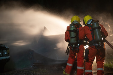 Fototapeta premium Firefighters spraying water to put out a brutal fire on the car.