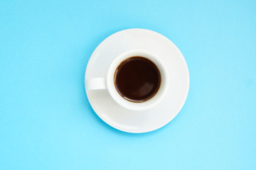 White cup of strong coffee on blue background Top view