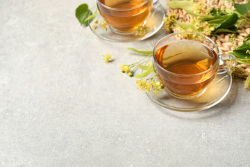 Tasty tea and linden blossom on light grey table. Space for text