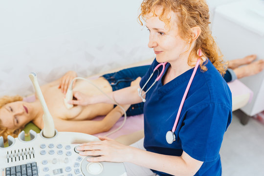 Red haired doctor using ultrasound scanner performing examination of breast of her patient gynecology mammalogy cancer awareness feminine health medical concept.