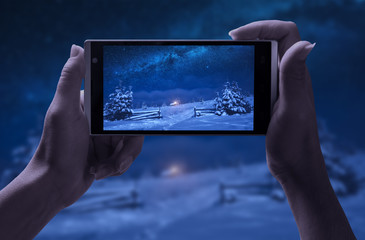 Girl take a picture of winter snowy village at night