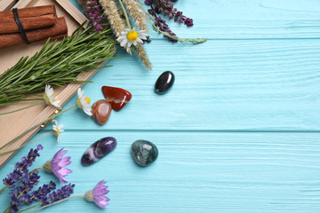 Gemstones and healing herbs on light blue wooden table, flat lay. Space for text