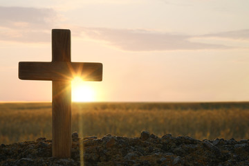 Wooden Christian cross outdoors at sunrise, space for text. Religion concept