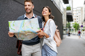 Happy smiling woman and man in love walking with map in the city