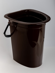 a dark brown plastic bucket instead of a toilet in the house