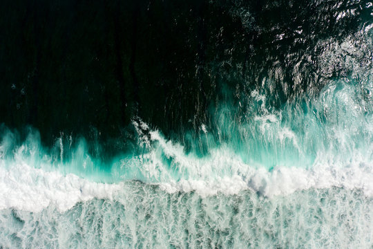 Top aerial view of giant ocean waves crashing and foaming.