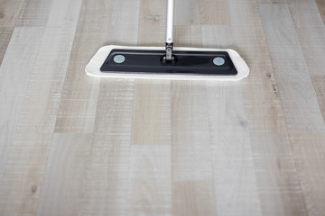cleaning and purity concept - close up of wooden floor with mop and copy space