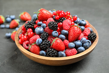 Mix of different fresh berries in bowl on grey table