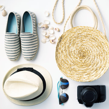 Flat lay traveler accessories on white background with straw hat, summer shoes, camera, bag and sunglasses.