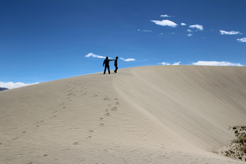 View of 2 men standing on top of a sand dune in a sunny day, Tibet, China