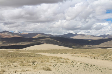 View of the mountain and sand dune with dirt road near Tingri on the way to Everest Base Camp, Tibet, China