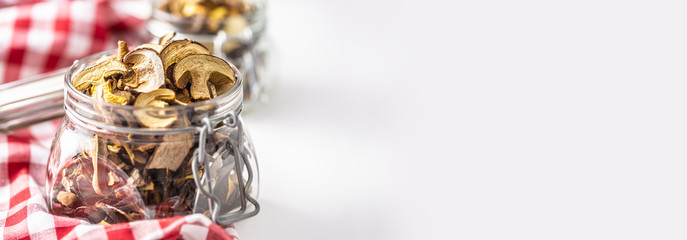 Dried mushrooms in a glass jar on a red checkered tablecloth