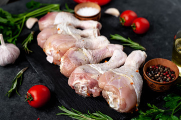 raw chicken legs with spices and ingredients on a stone background