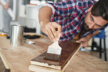 Carpenter painting a raw board with a protective preparation