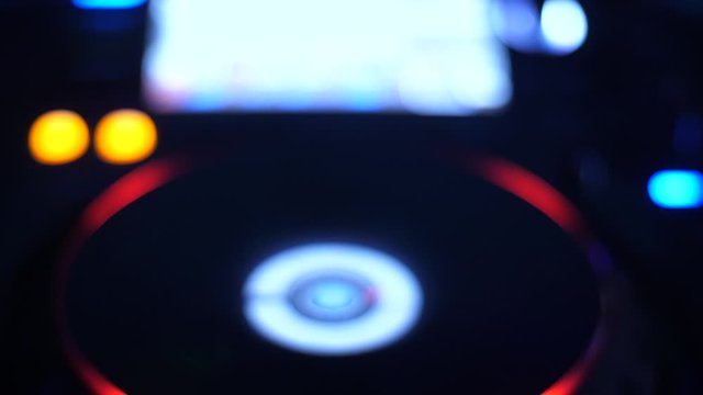 DJ equipment playing records at a club in dim light. CDJ Turntable.