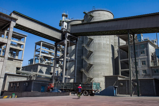 Mynaral/Kazakhstan: Modern Jambyl Cement plant. Industrial buildings, cement silos, truck and worker on blue sky.