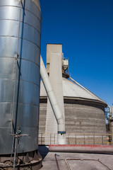 Mynaral, Kazakhstan. Jambyl Cement plant. Tower and mixing silo on clear blue sky.